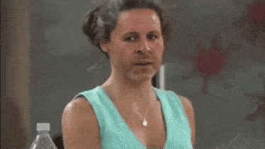 a woman in a blue tank top drinking from a white mug