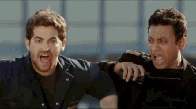 two men are standing next to each other and one of them is holding a knife .