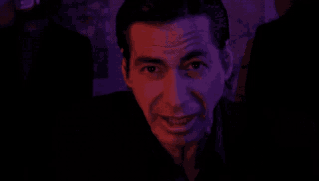 a man in a dark room with purple lights on his face