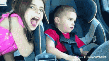 a boy and a girl are sitting in a car seat .