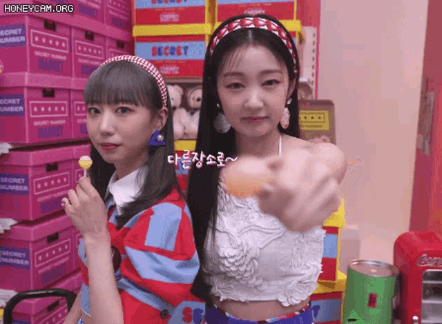 two girls standing next to each other in front of boxes that say secret number on them