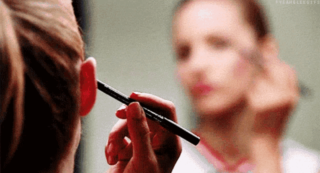 a woman is applying makeup to her face with a brush .