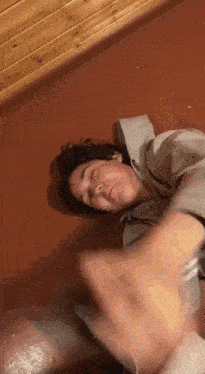 a young man is laying on the floor with his eyes closed and making a funny face .