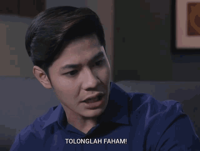a man in a blue shirt with the words tolonglah faham written below him