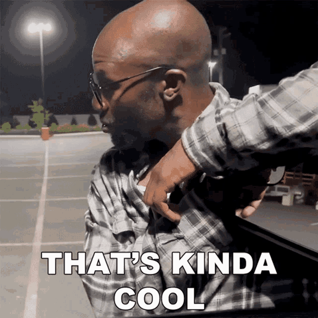 a man in a plaid shirt says that 's kinda cool in a parking lot
