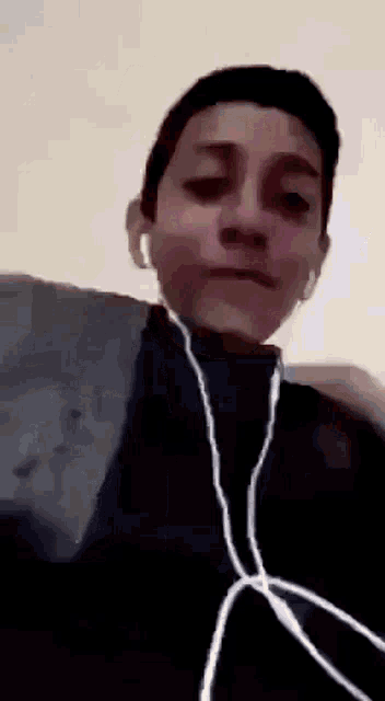 a young boy wearing earbuds is looking at the camera .
