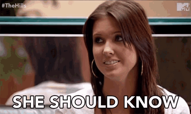 a woman says she should know while smiling and looking at the camera