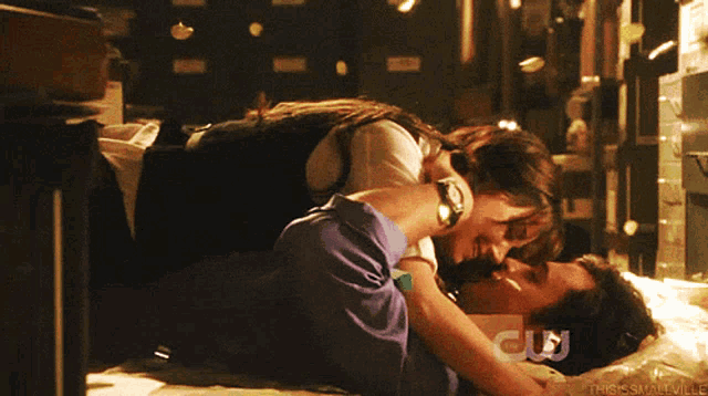 a couple kissing on a bed with a cw logo behind them