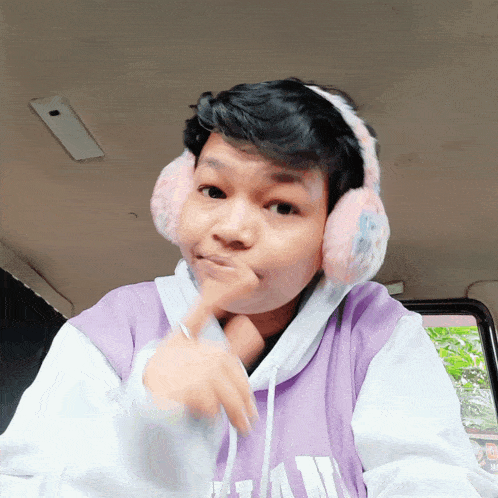 a person wearing ear muffs and a purple hoodie with the letter a on the front