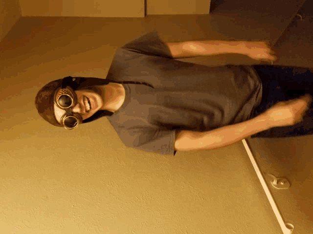 a man wearing a hat and goggles is standing in front of a wall
