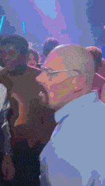 a crowd of people are gathered in a dark room with a blue light behind them that says ' e '