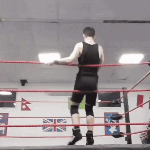 a man in a black tank top is standing in a ring
