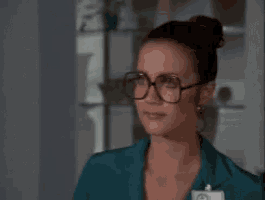 a woman wearing glasses and a name tag is standing in front of a window .