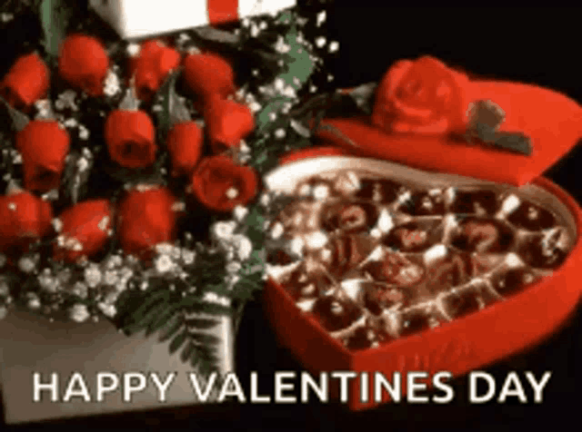 a red heart shaped box filled with chocolates next to a bouquet of red roses