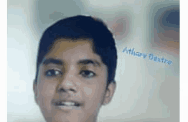 a close up of a young boy 's face with the name atharav written on the bottom .