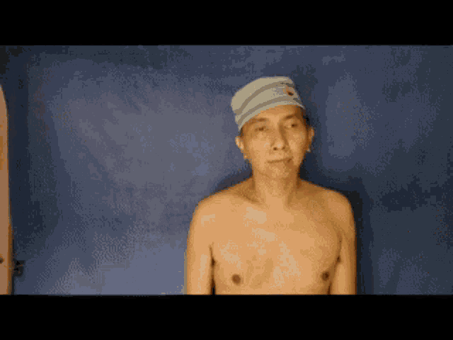 a man without a shirt is wearing a striped hat