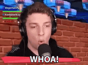 a young man wearing headphones is talking into a microphone and saying whoa .