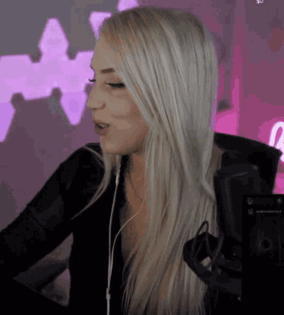 a woman wearing headphones stands in front of a microphone with a purple background