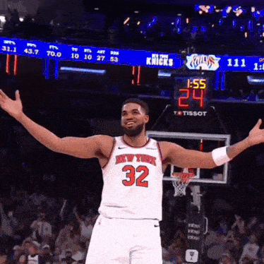 a man in a new york knicks jersey stands in front of a scoreboard