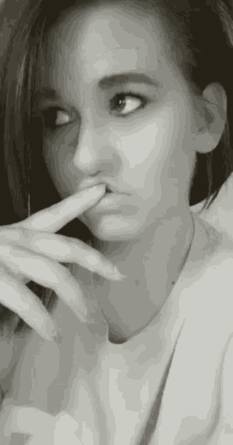 a black and white photo of a woman with her finger to her mouth