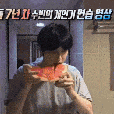 a man is eating a watermelon in front of a wall with chinese writing