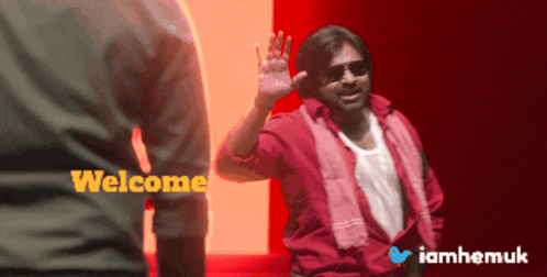 a man in a red shirt is waving in front of a red and white background that says welcome