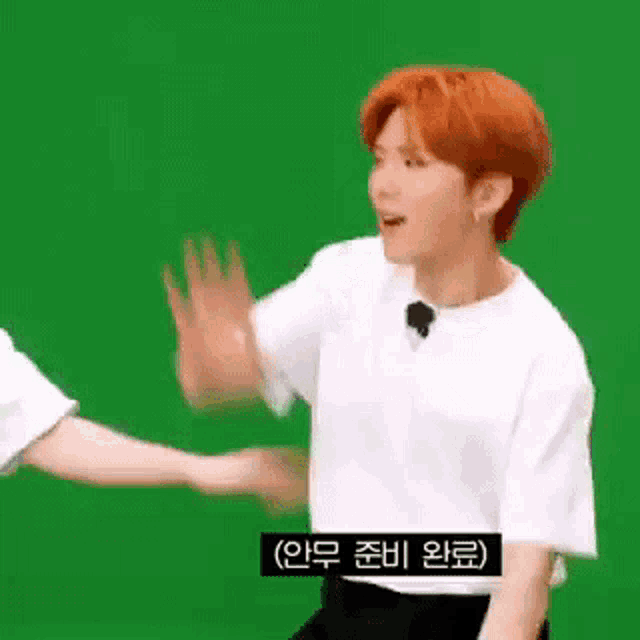 a man with red hair is giving another man a high five while standing in front of a green screen .