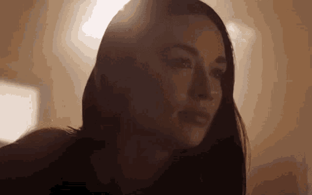 a close up of a woman 's face with the sun shining through the window behind her .