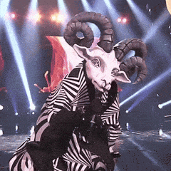 a goat with horns is standing on a stage with a microphone