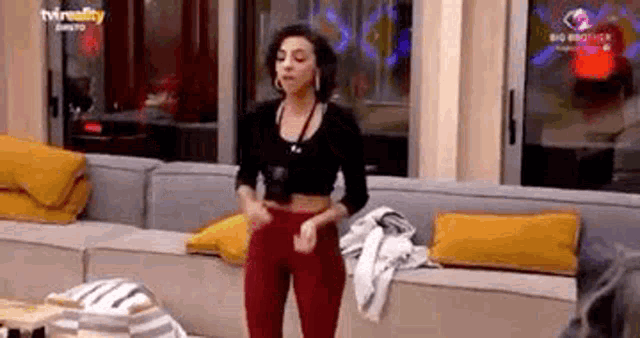 a woman is standing in front of a couch in a living room and dancing .