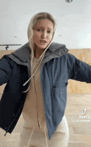 a woman wearing a blue jacket and a white hoodie is dancing .