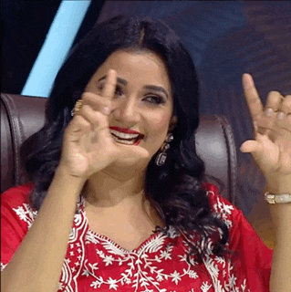 a woman in a red and white dress is smiling and making a peace sign