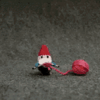 a crocheted gnome is holding a ball of yarn