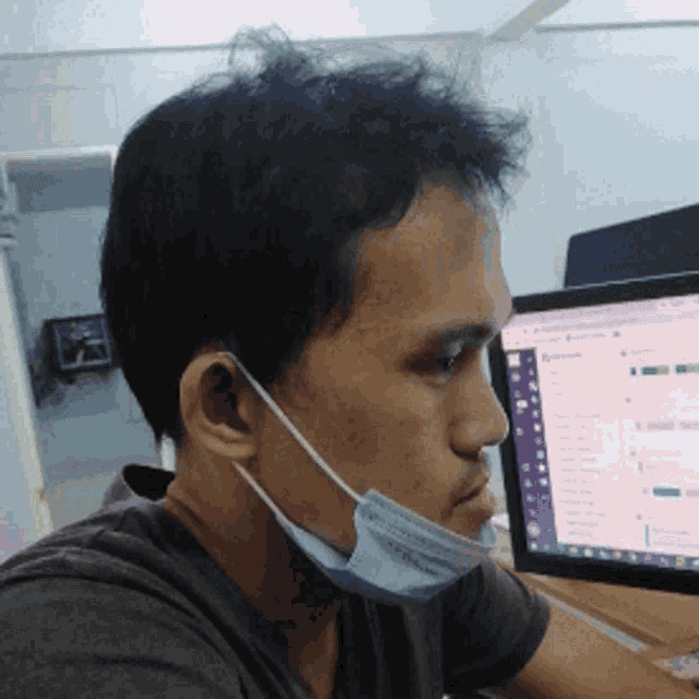 a man wearing a face mask is sitting in front of a computer