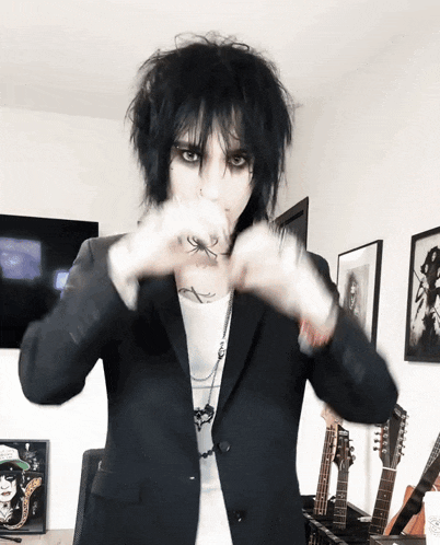 a man in a black jacket making a heart with his hands