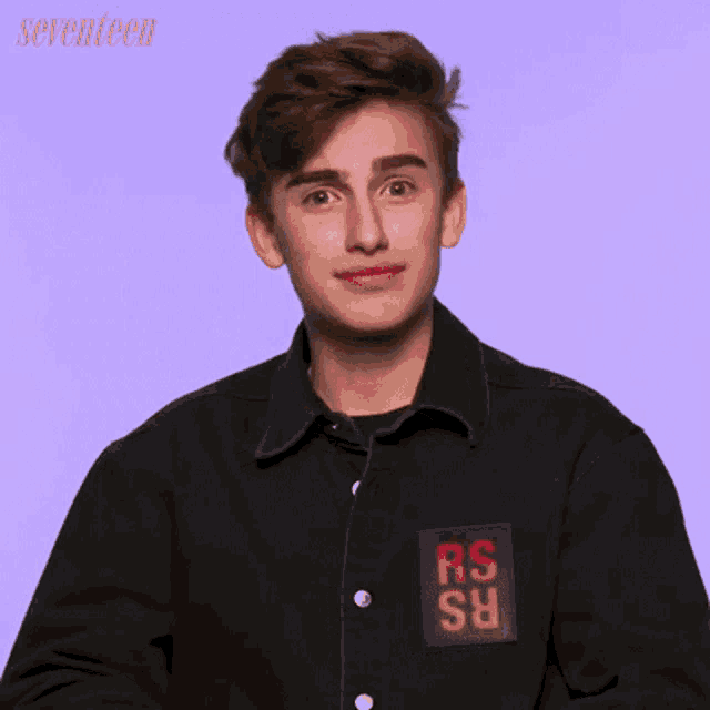 a young man wearing a black jacket with rs on the sleeve