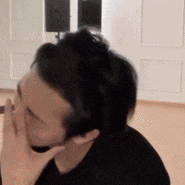 a man is covering his face with his hand while sitting in a room .