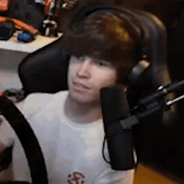 a man wearing headphones is sitting in a chair with a microphone in front of him .