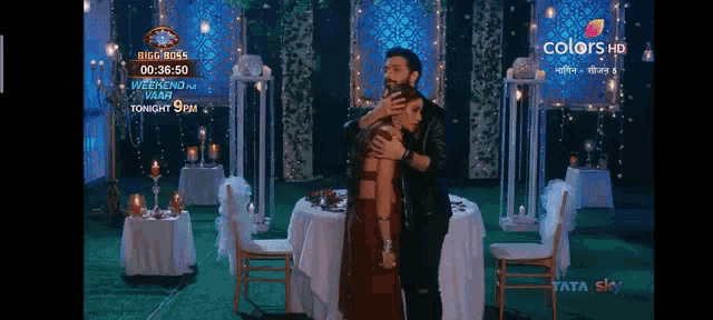 a man and a woman are hugging each other in front of a table with candles on it .