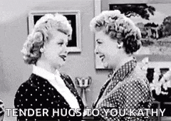 two women are hugging each other in a living room .