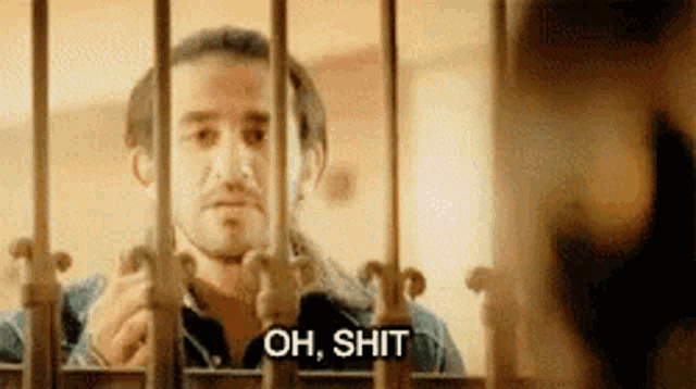 a man is behind bars with the words `` oh , shit '' written on his face .