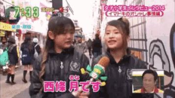 two girls are talking to each other on a street with 7:33 in the upper left corner