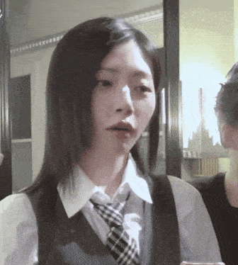 a woman wearing a white shirt and a plaid tie looks surprised