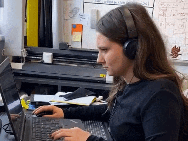 a woman wearing headphones is typing on her laptop