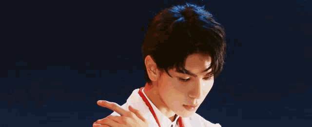 a young man in a white coat and red tie is pointing at something