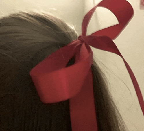 a close up of a person 's hair with a red bow