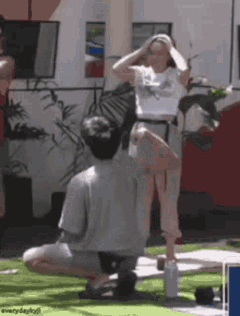 a man is kneeling down in front of a woman who is holding her hair