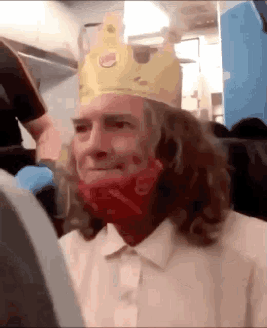 a man wearing a burger king crown and a red mask