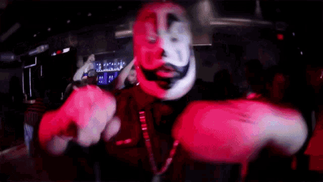 a man wearing a clown mask is dancing in front of a crowd