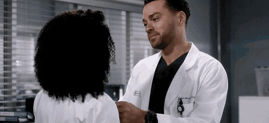 a man and a woman are standing next to each other in a lab coat .